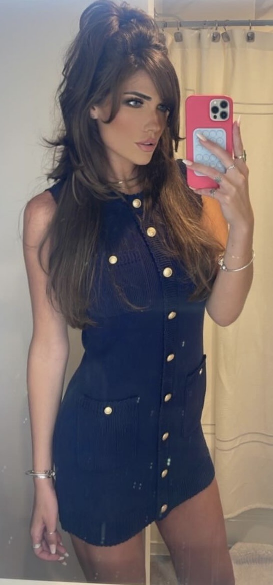 Morgan wearing a navy mini dress with gold buttons