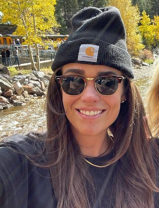Morgan smiling outdoors in sunglasses and a beanie