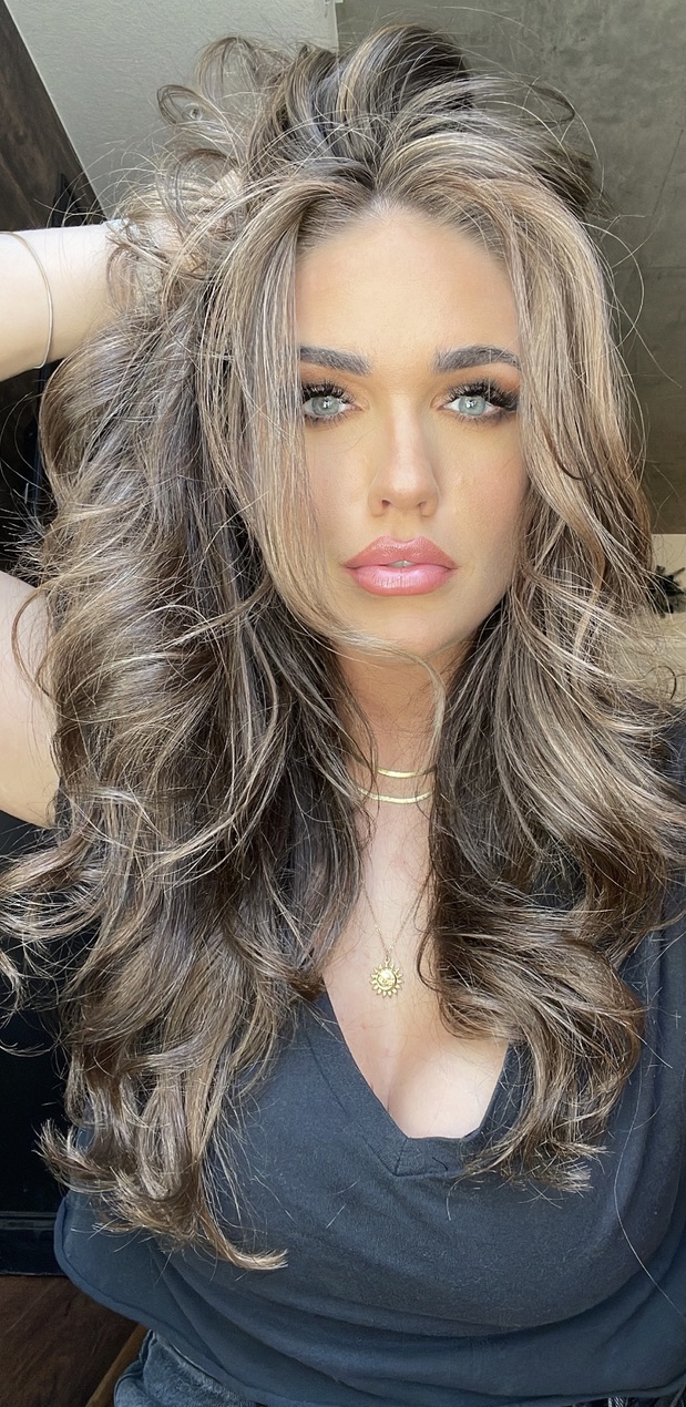 Portrait of Morgan with long wavy hair wearing a black top